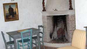 Ein Zimmer mit Kamin, einem Tisch mit Stühlen und einem Gemälde an der Wand.
