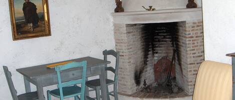 A room with a fireplace, a table with chairs, and a painting on the wall.