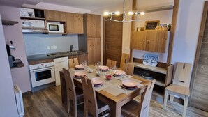 Une cuisine compacte dotée de meubles en bois, d’un four à micro-ondes, d’un évier et d’un coin repas aménagé pour quatre personnes.