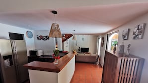 Una cocina moderna con una isla central, electrodomésticos de acero inoxidable y un área de comedor con sofá.