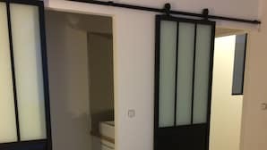 Une chambre à coucher comprenant un lit, une armoire et une salle de bain accessible par une porte coulissante.