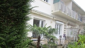 Une cour avec un chemin en pierre, des plantes en pot et un bâtiment doté d’un balcon.