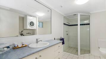 Et moderne badeværelse med et stort spejl, en vask, en brusekabine med glasvægge og et toilet.