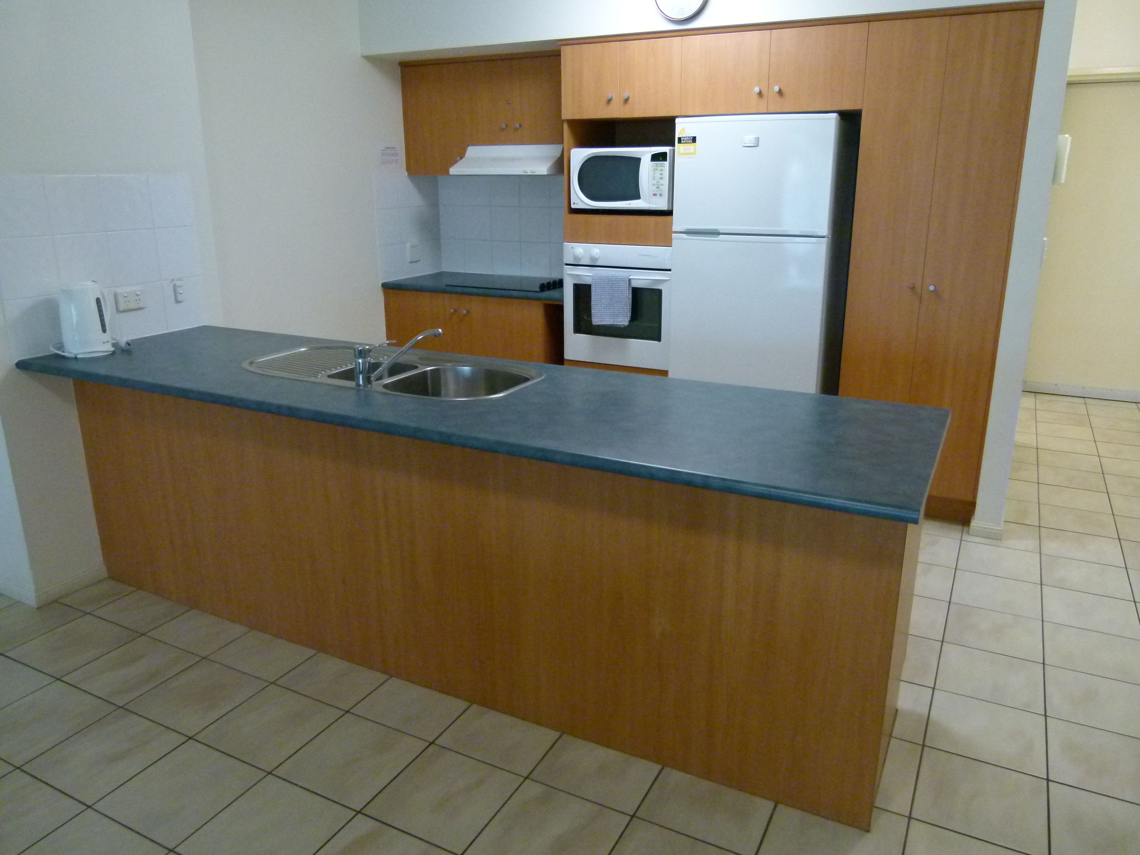 A compact kitchen with a sink, microwave, and refrigerator.