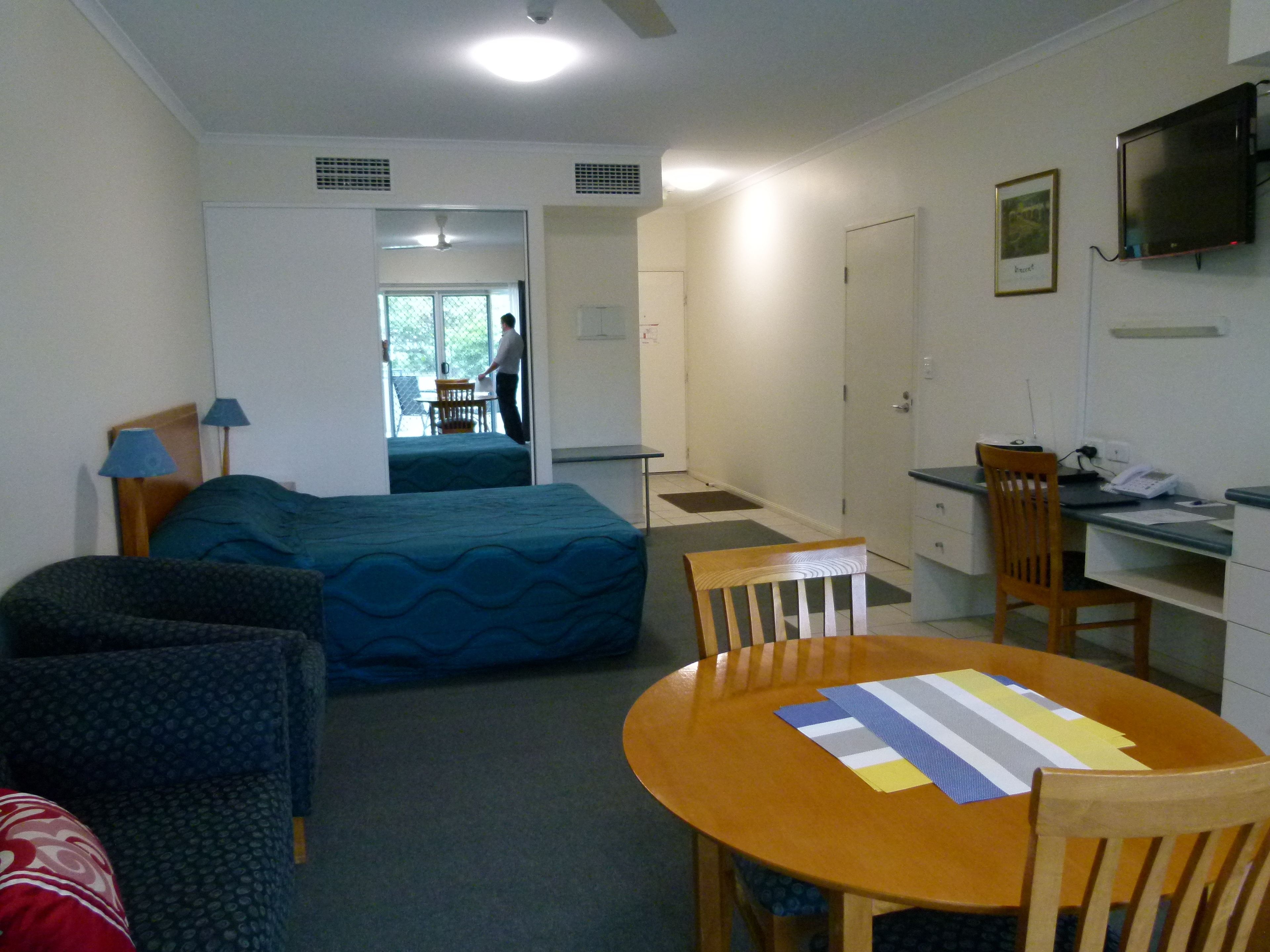 Une chambre d’hôtel équipée d’un lit, d’un bureau, d’une chaise, d’une table et d’un téléviseur.