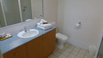 Un bagno con lavandino, specchio, WC e cestino.