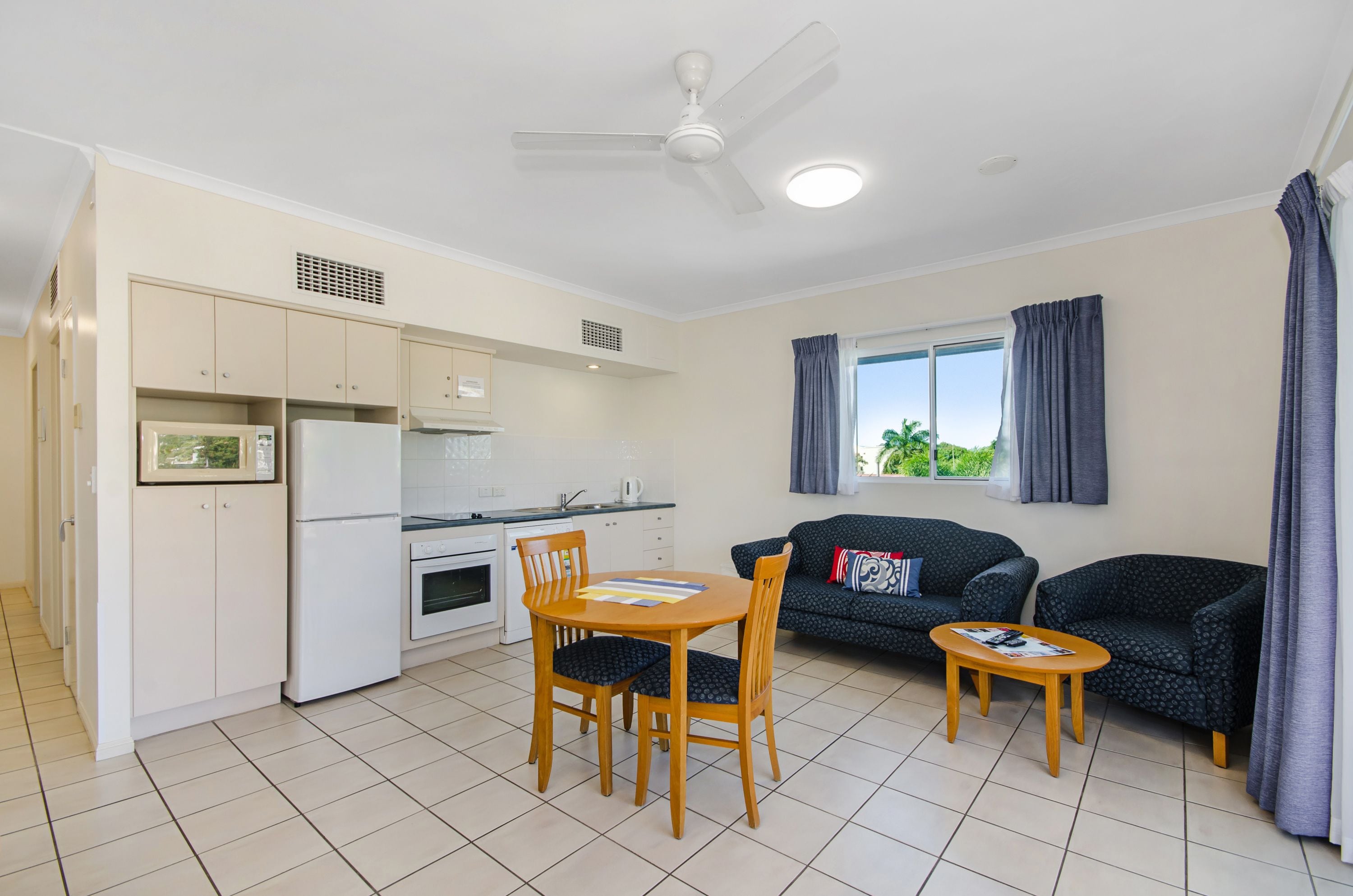 Un espacio habitable compacto con kitchenette, una zona de comedor con mesa y sillas, un sofá y una pequeña mesa de centro.