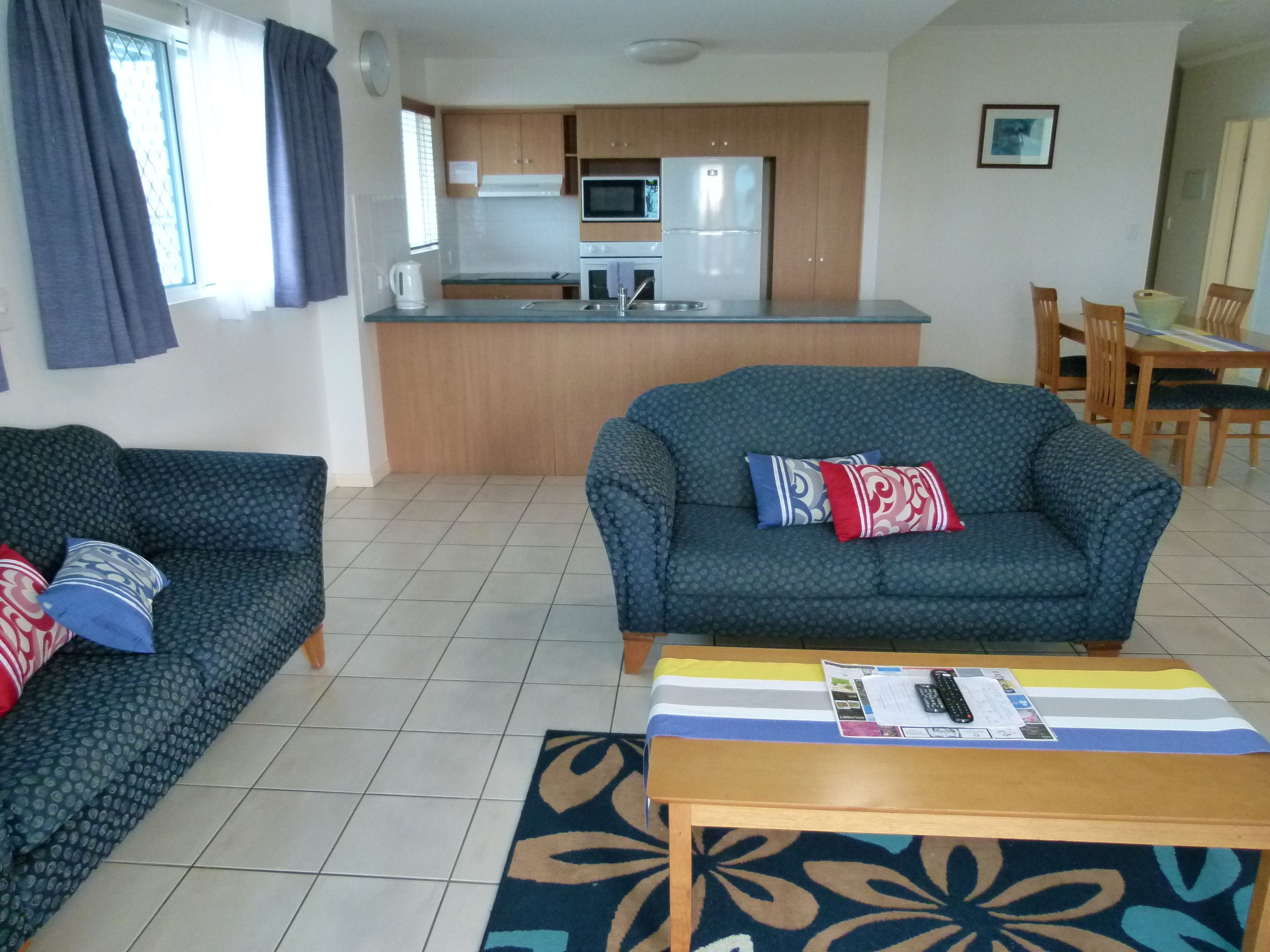 A living room with a sofa, a coffee table, and a dining area with chairs and a table.
