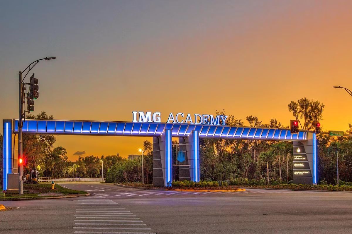 Eingang der IMG Academy mit einem blau beleuchteten Bogen, einem Zebrastreifen und Ampeln.