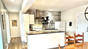 Een moderne keuken met witte kastjes, een centraal eiland en een eethoek met een houten tafel en stoelen.