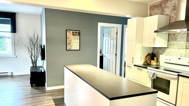 Een moderne keuken met een centraal eiland, witte kasten en een ingebouwde oven.