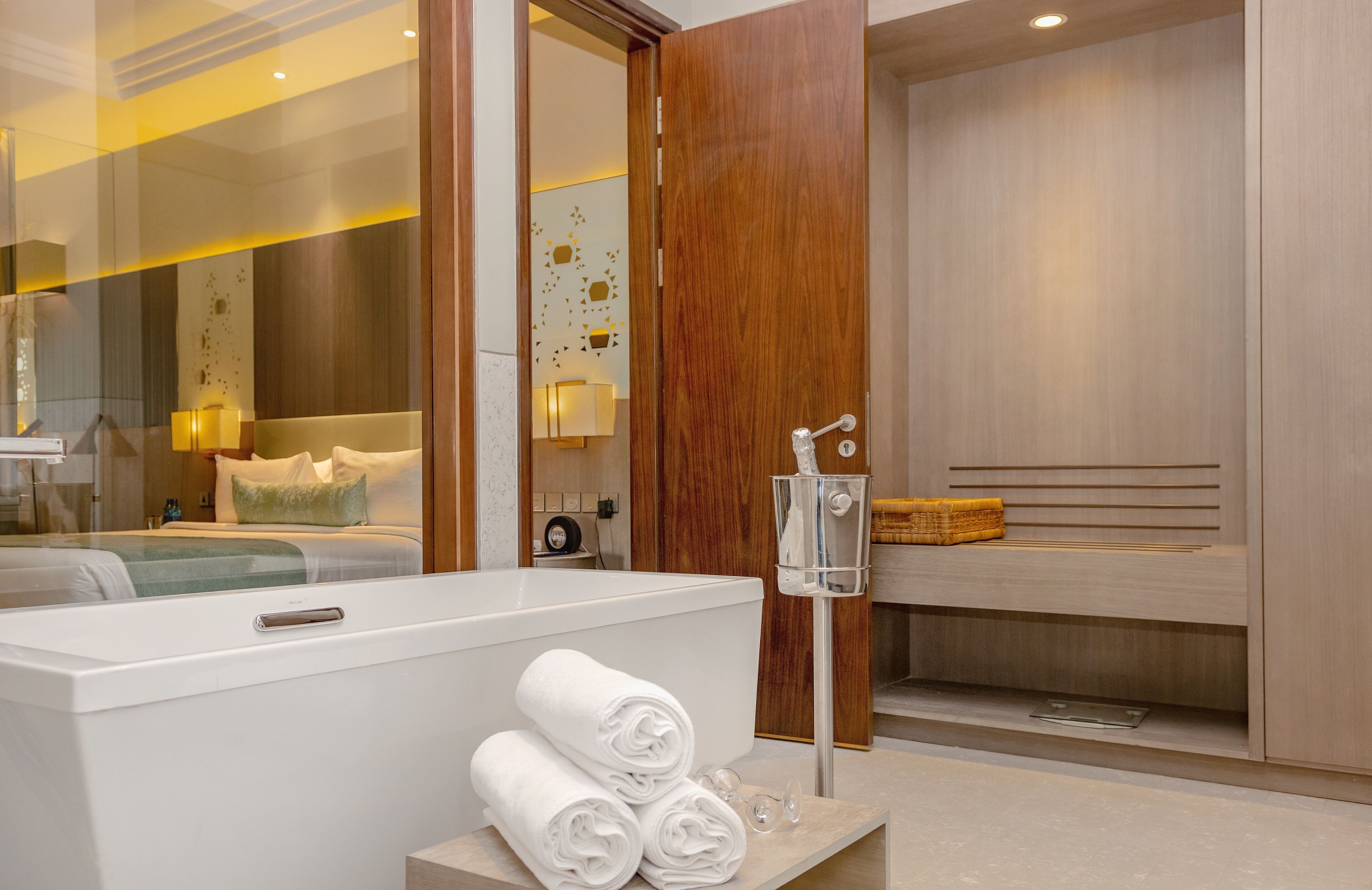 A modern bathroom with a large bathtub, a bench, and a mirror.