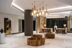 A modern lobby with a marble floor, wooden seating, a reception desk, and pendant lighting. - Neelkanth Sarovar Premiere (Lusaka)