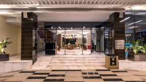 A hotel entrance with a glass door, a check-in counter, and a reception area. - Neelkanth Sarovar Premiere (Lusaka)