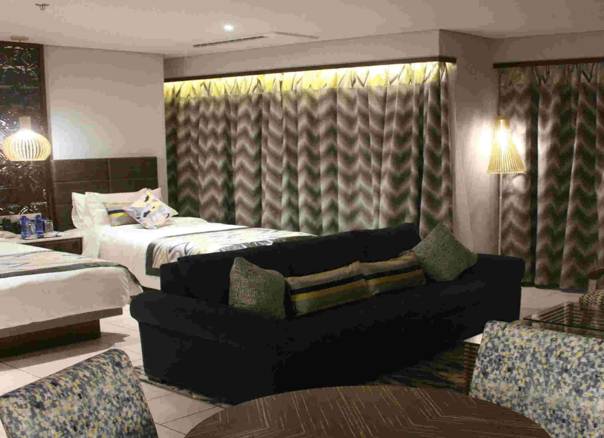 Une chambre d’hôtel avec un lit, un canapé, une table basse et une lampe.