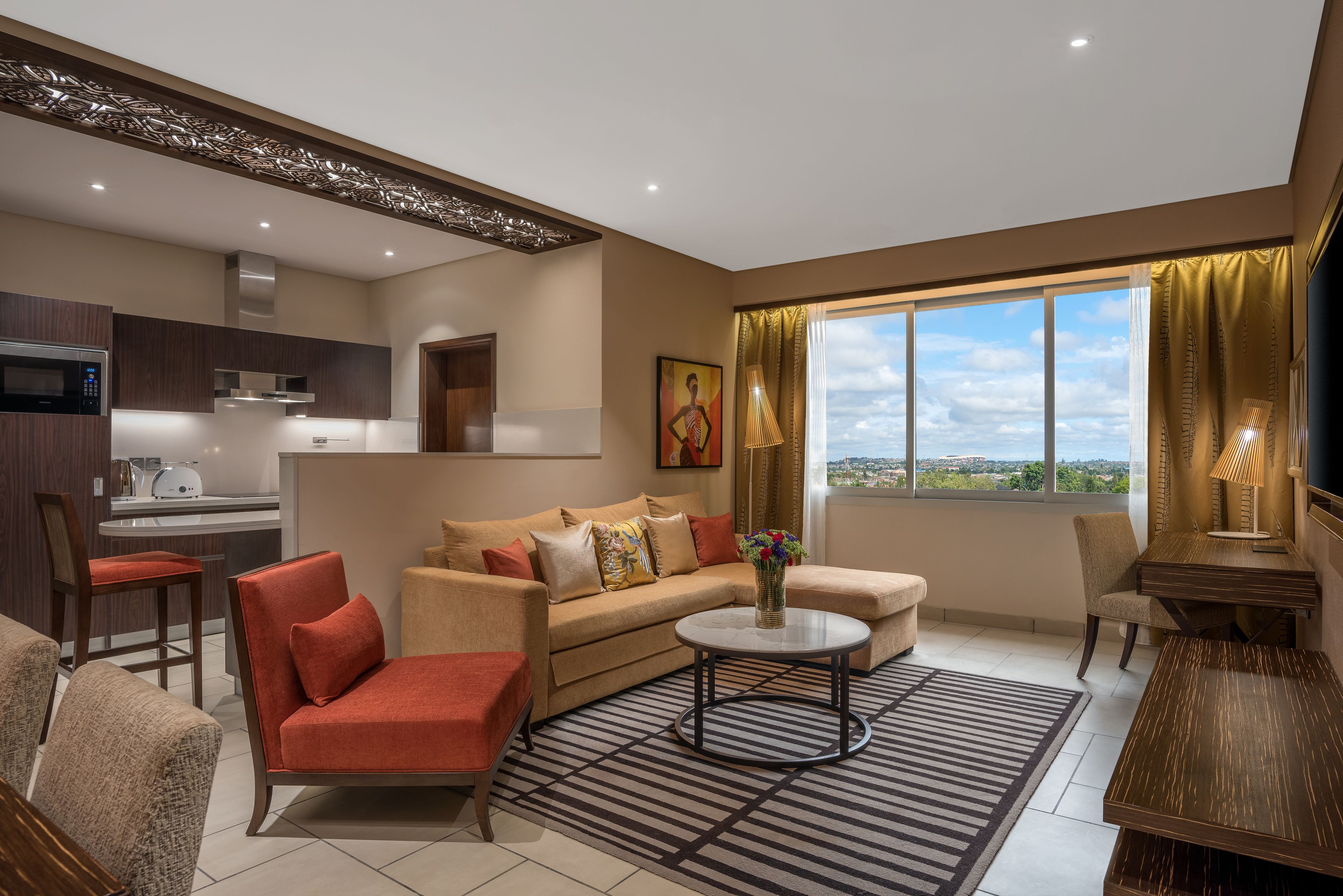 A modern living room with a sofa, armchairs, a coffee table, and a view of the city through large windows.
