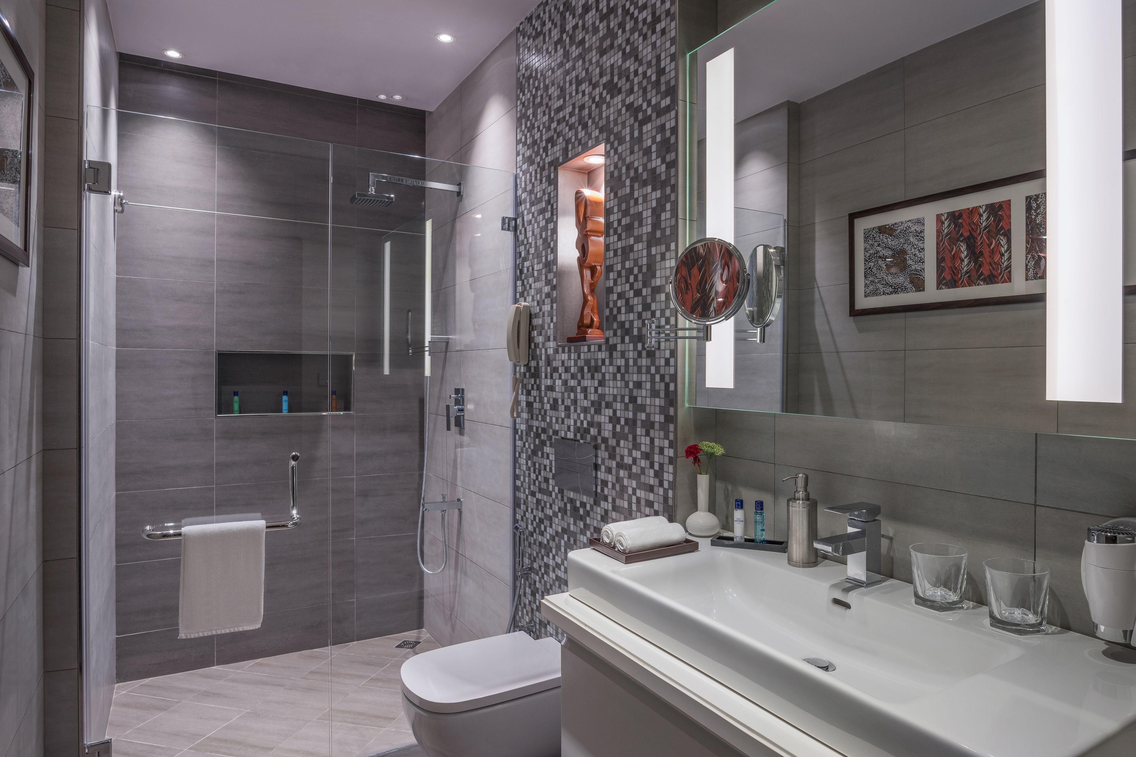 Een moderne badkamer met douche, toilet en wastafel.