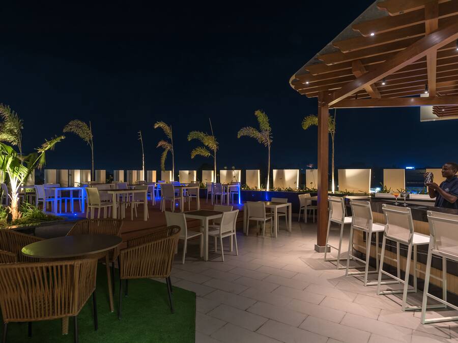 An outdoor dining area with tables and chairs, a bar, and a covered seating area.