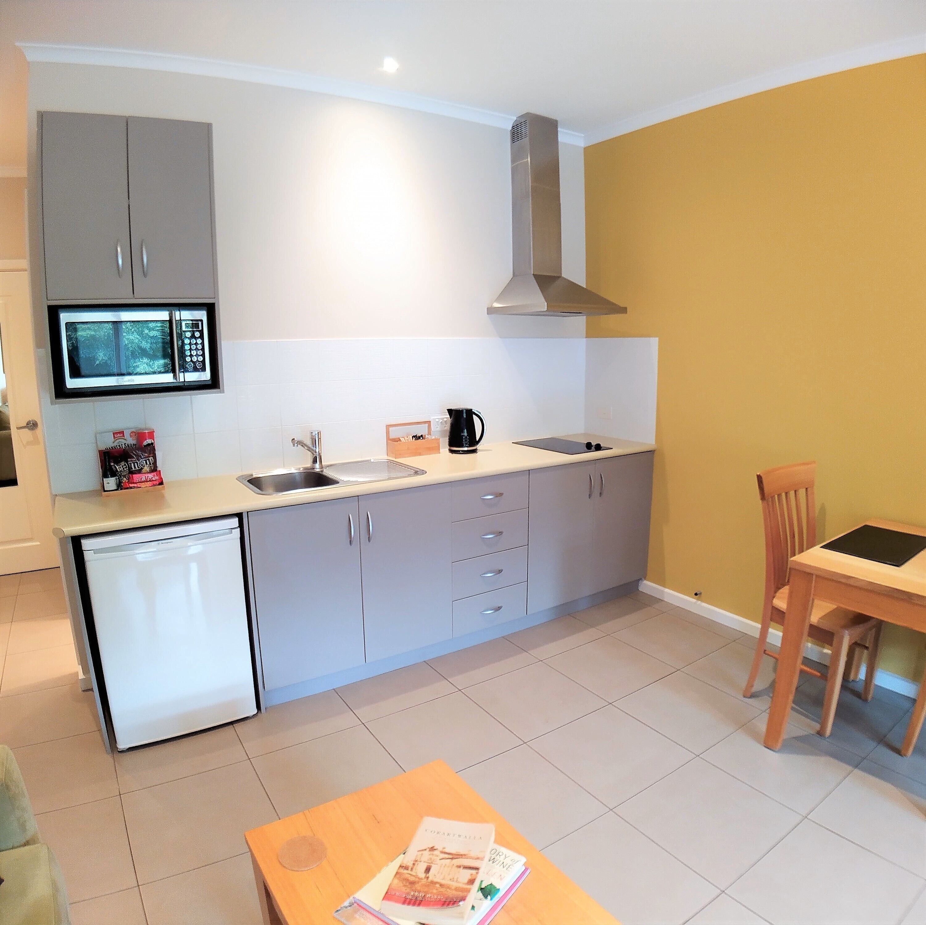A compact kitchen with a microwave, sink, and a small dining area with a table and chair.