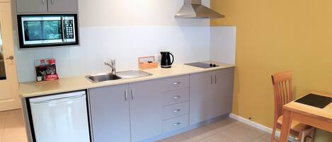 A compact kitchen with a microwave, sink, and a small dining area with a table and chair.