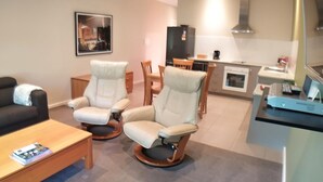 Un salon moderne comprenant un canapé, deux fauteuils, une table basse et un coin repas avec une table et des chaises.