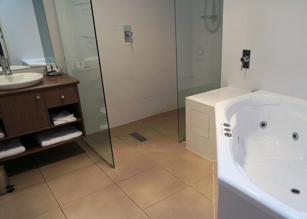 A modern bathroom with a glass shower enclosure, a white bathtub, and a wooden vanity with towels. - A Must At Coonawarra (Penola)