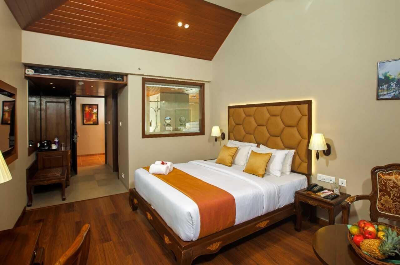 Una habitación de hotel con una cama grande, piso de madera, un escritorio y una silla.