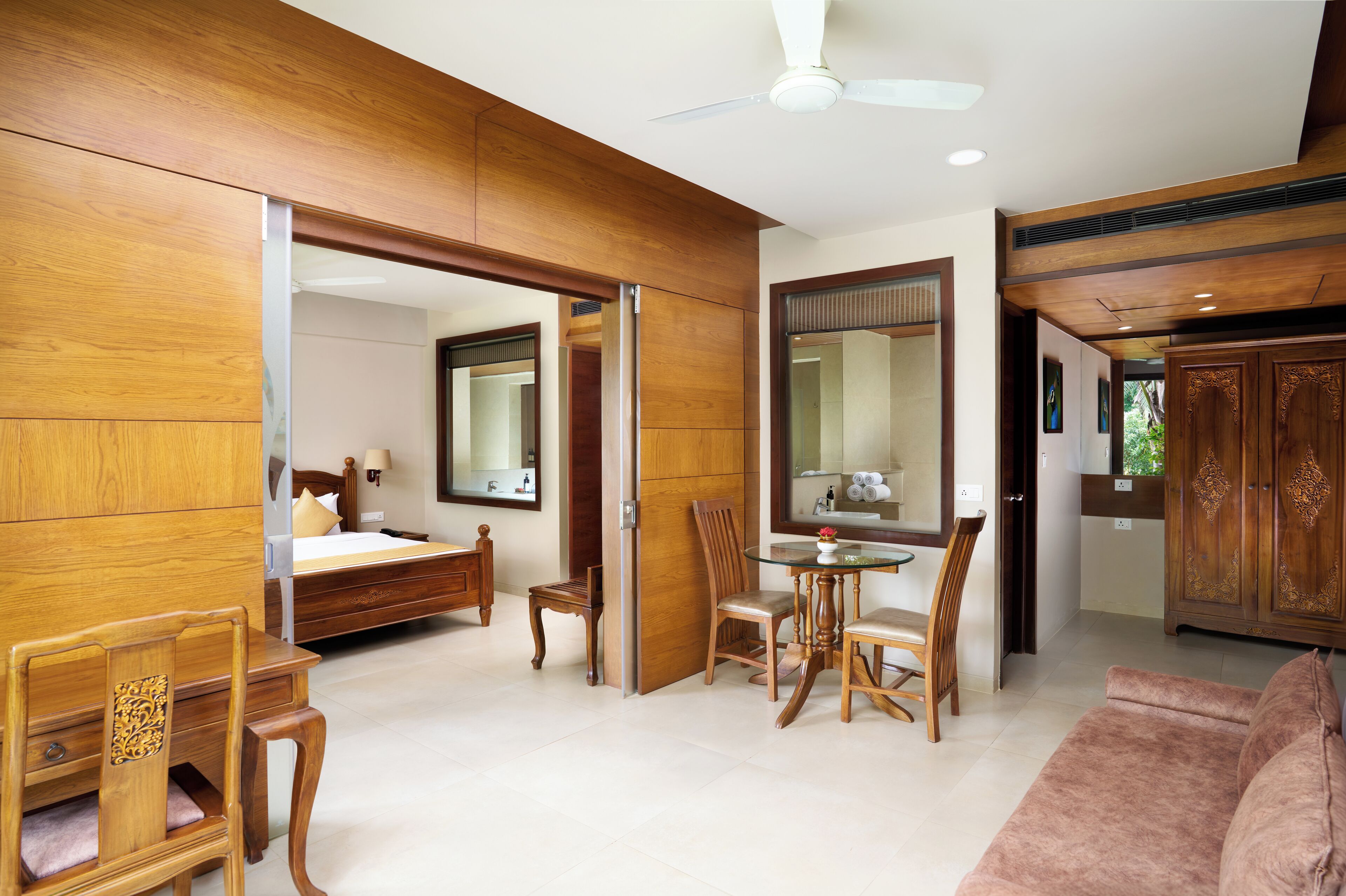 A spacious room with a bed, a dining table with chairs, a sofa, and a cabinet.
