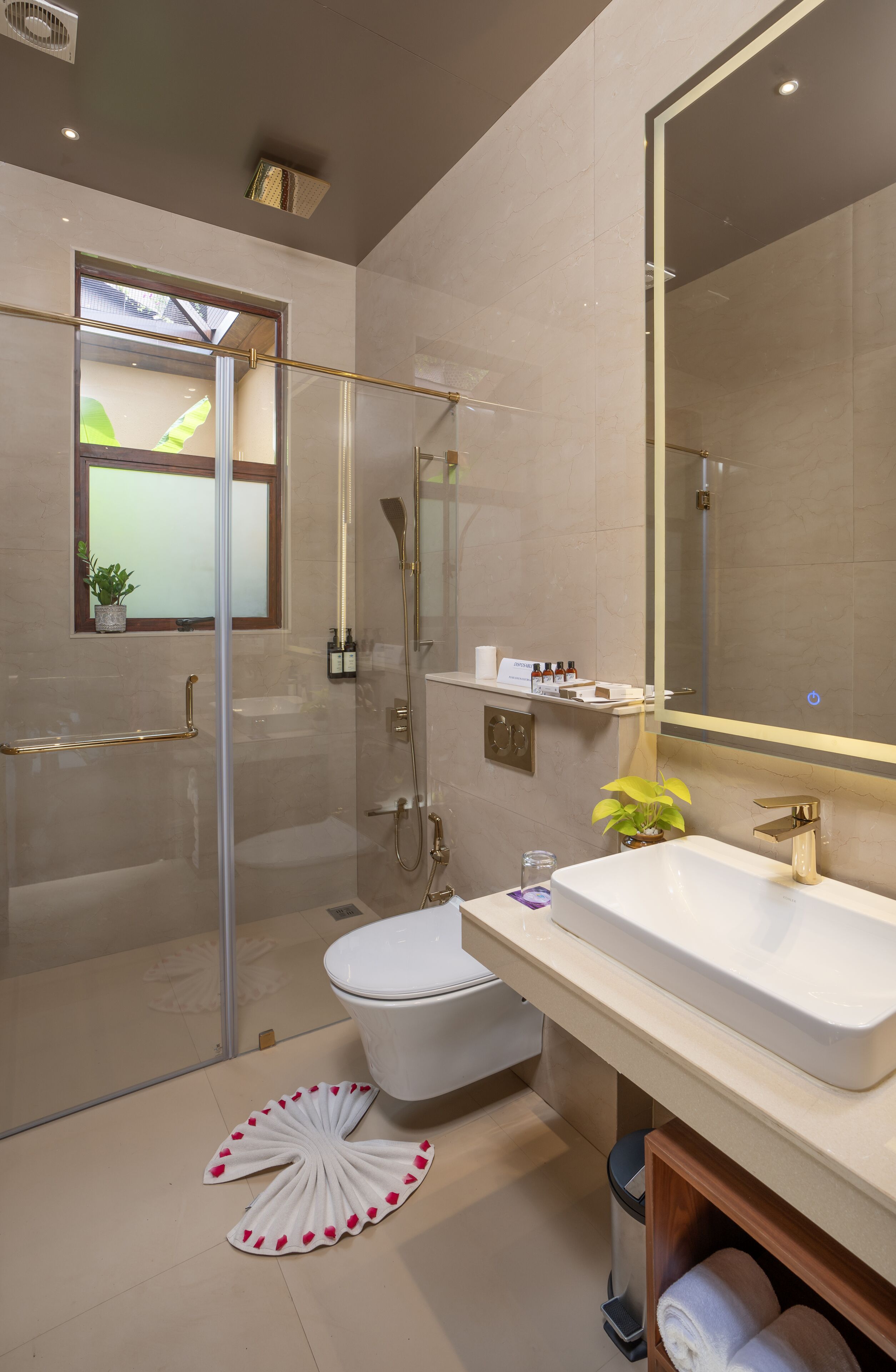 A modern bathroom with a glass-enclosed shower, a white toilet, a large mirror, and a vanity with a sink.