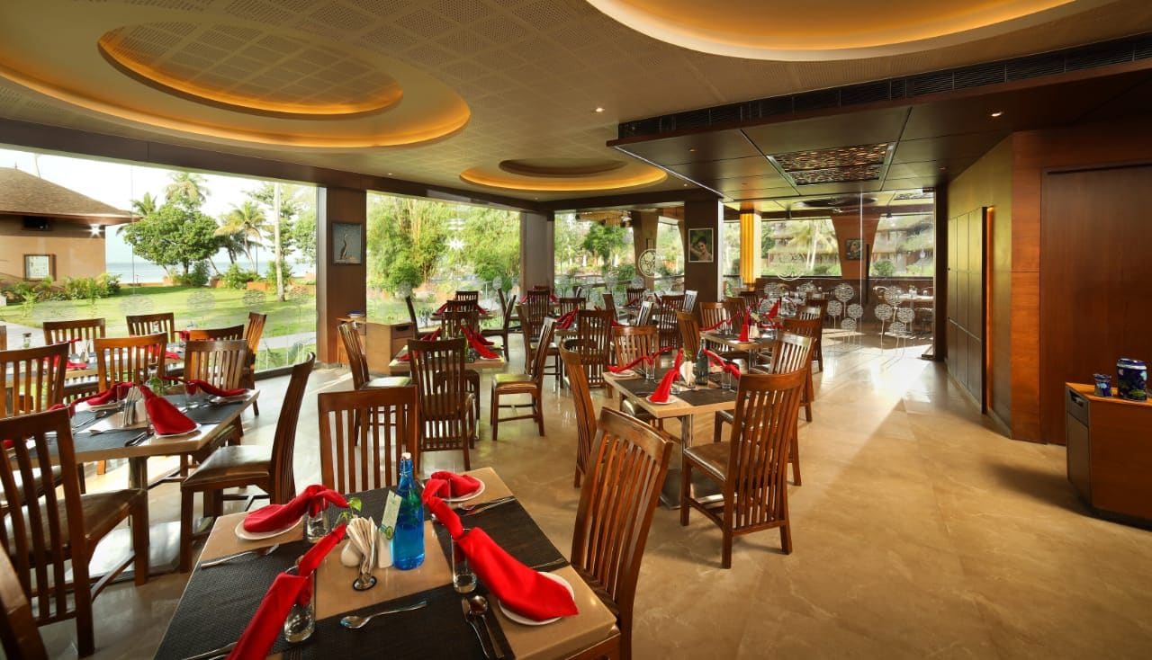 A restaurant with multiple dining tables and chairs, some with red napkins.