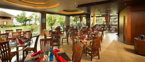 A restaurant with multiple dining tables and chairs, some with red napkins.
