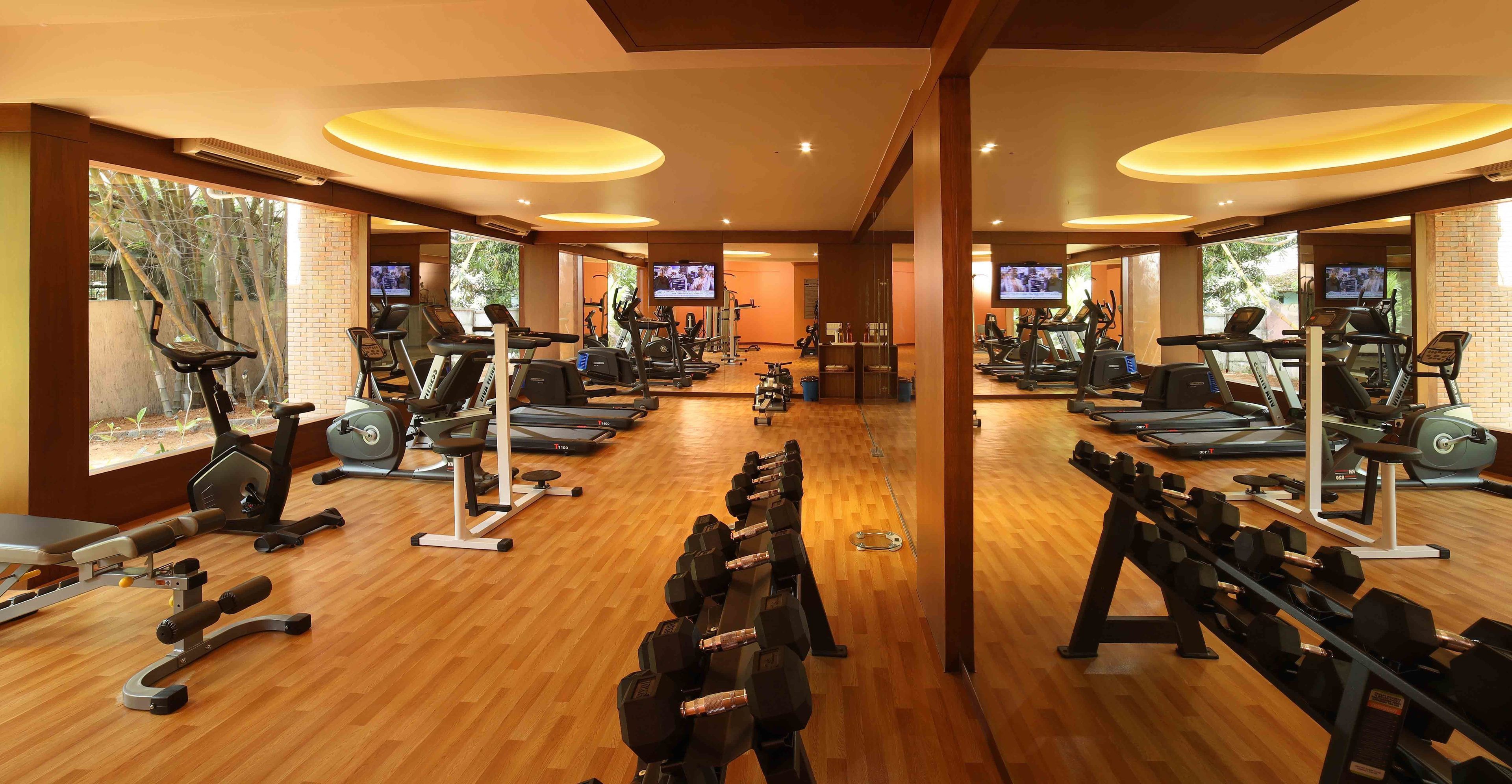 Un gimnasio con cintas de correr, elípticas y pesas libres dispuestas en filas.