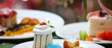 A dessert plate with various sweets, including a layered cake, a scoop of blue ice cream, and a piece of cake with a cherry on top.