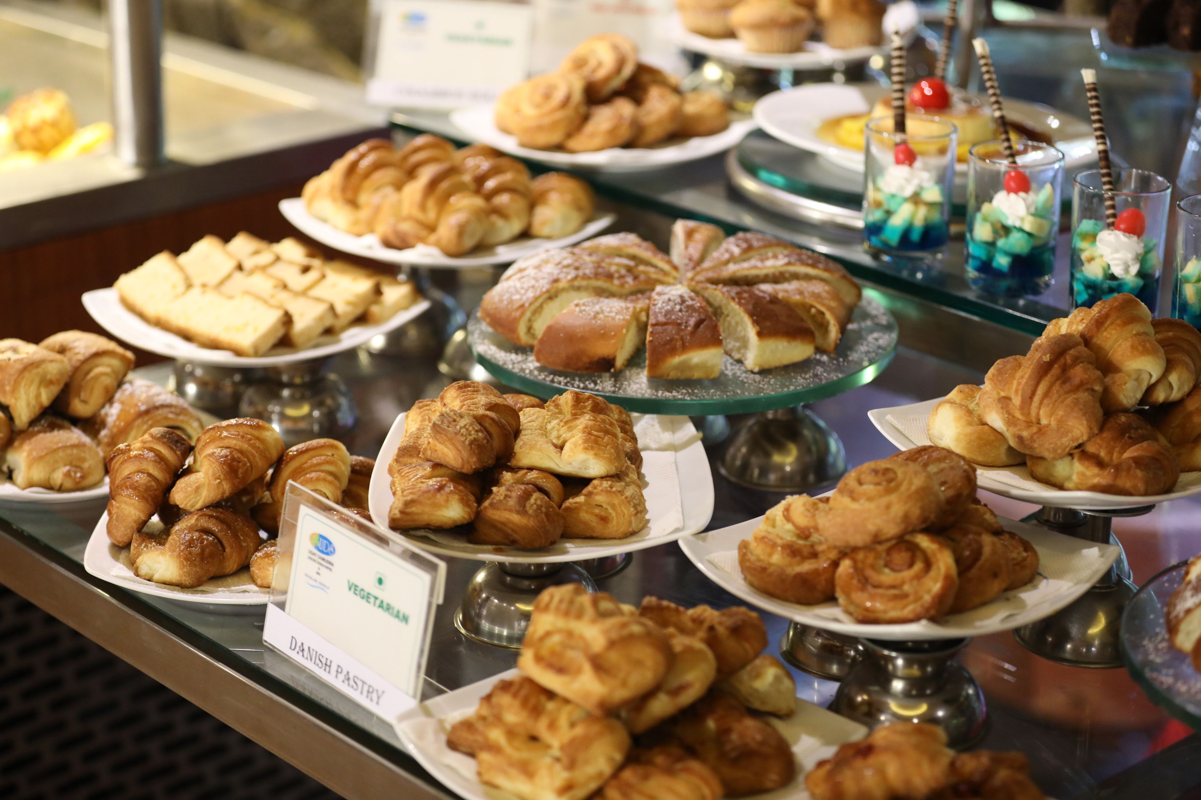 Variedad de pasteles y postres expuestos en múltiples platos y bandejas.