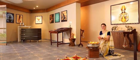 A room with a bed, a desk, a chair, a small altar with a lamp, and a statue.