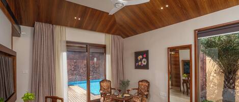Una habitación amplia con una cama grande, una mesa de comedor con sillas, una piscina pequeña y vistas al exterior.