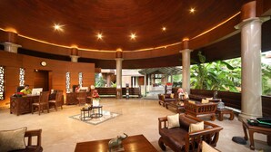 A spacious lobby with wooden furniture, a reception desk, and a view of lush greenery outside. - Uday Backwater Resort (Ambalapuzha)