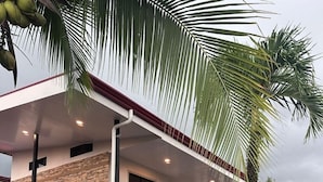 Een modern huis met twee verdiepingen, een overdekte veranda, een trap en een verzorgde tuin.