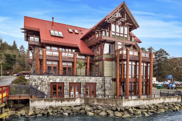 A large, multi-story building with a stone facade, wooden balconies, and a red roof.
