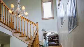 A wooden staircase with a chandelier, a window, and framed artwork on the wall. - 3 Bedroom Farm Home. Sleeps 10 - One Mile Outside Joseph, Oregon. The Evans Farm (Joseph)