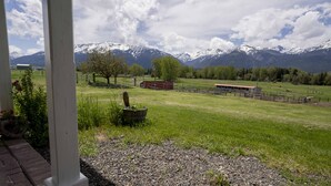 A rural landscape with a grassy field, a wooden fence, and a red building. - 3 Bedroom Farm Home. Sleeps 10 - One Mile Outside Joseph, Oregon. The Evans Farm (Joseph)
