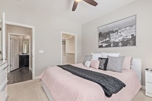 A bedroom with a bed, a ceiling fan, a cityscape painting, and a walk-in closet. - Luxurious Resort Condo in Ocotillo with Pool and Canal Views! (Chandler)