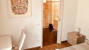 A bedroom with a bed, a bedside table, a nightstand, a wooden dresser, and a door leading to a bathroom. - CaMé (Alzano Lombardo)