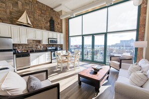 A spacious living area with a large window, a kitchen with white cabinets, and a cozy seating area with a sofa and chairs. - Spectacular Turn-Key Waterfront Getaway For Six!! (Sandusky)