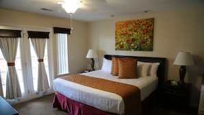 A hotel room with a large bed, two bedside lamps, a painting on the wall, and a window with curtains. - Grand Crowne golf course view Branson Surrey w/master hot tub! (Branson)