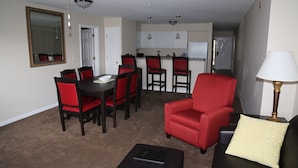 A living room with a dining area, a red armchair, a black sofa, and a lamp. - Grand Crowne golf course view Branson Surrey w/master hot tub! (Branson)