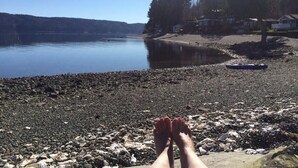 Een uitzicht op een meer met een rotsachtige oever, een boot en huizen op de achtergrond.