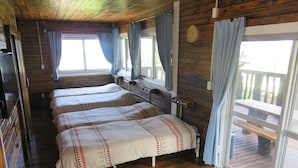 A cabin with three wooden beds, a wooden ceiling, and large windows with curtains. - Okinawa Freedom (Nakijin)
