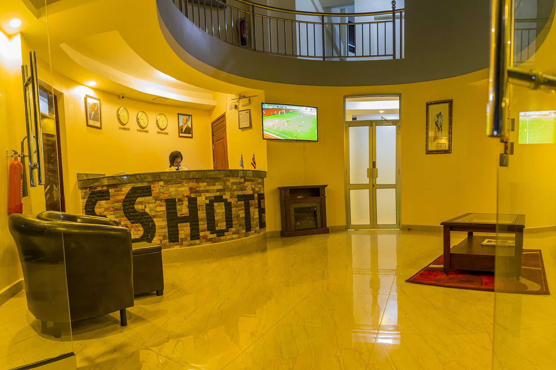 A lobby with a reception desk, a fireplace, a television, and a seating area.
