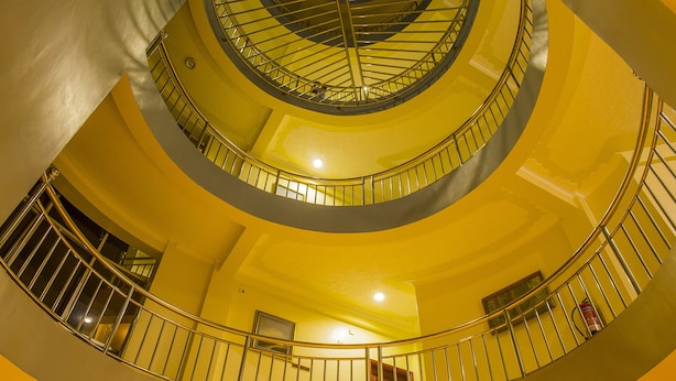 Un interior de varios niveles con una escalera de caracol, barandillas de metal y una decoración amarilla.